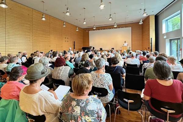 Quelle: Katholische Akademie Freiburg, Palliative Care Forum In einem Raum sitzen viele Menschen und hören einem Redner zu
